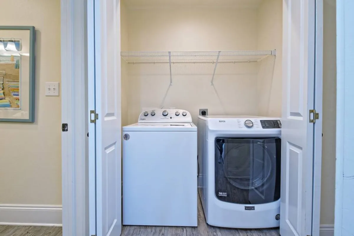A utility room with a modern washing machine and dryer, with organized shelving above. The space is clean, practical, and designed for convenience, supporting efficient laundry for busy families or longer stays.